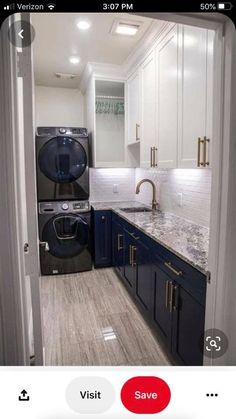 a washer and dryer in a kitchen with dark blue cabinets, marble counter tops