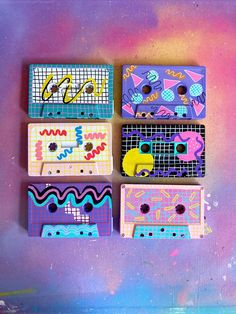 four different colored boxes sitting on top of a purple and blue surface with colorful designs