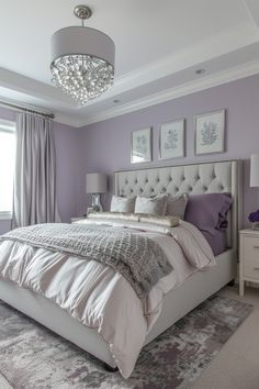 a bedroom with purple walls, white bedding and chandelier hanging from the ceiling