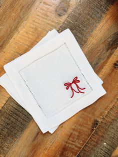 three white napkins with red bows on them sitting on a wooden table next to each other