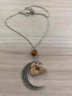 Crescent Moon Necklace. The necklace pictured is the one you will receive. 17 1/2" holey stone necklace on a 16K gold-plated over brass chain with silver finish. Silver-plated half moon pendant. Tiger Eye bead. Hag stones are said to have many uses. Protection, Meditation, Astral Travel, Cleansing Rituals, Divination, Connection with the spiritual realm or with ancestors who have passed on, just to name a few. BACK TO MY SHOP: https://www.etsy.com/shop/SeaByTheShore Use coupon code FREESHIP75 to Hag Stones, Astral Travel, Crescent Moon Necklace, Tiger Eye Beads, Celestial Jewelry, Moon Pendant, Moon Necklace, Brass Chain, Stone Necklace