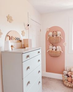 a white dresser sitting in a bedroom next to a wall with stuffed animals on it