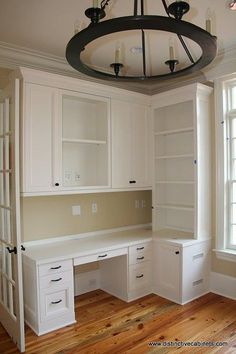 an empty room with white cupboards and drawers on the wall, along with a chandelier