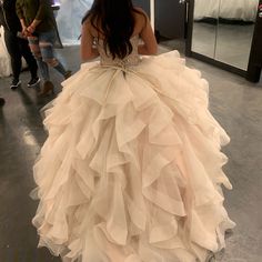 a woman in a ball gown is looking at herself in the mirror while another person stands nearby