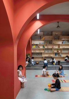 children are sitting on the floor and playing with toys in an indoor area that looks like a library