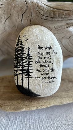 a rock with a poem on it sitting on a table next to a tree stump