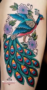 a colorful peacock tattoo on the back of a woman's arm with flowers and leaves