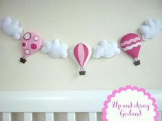 a pink and white baby crib with hot air balloons