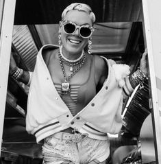 a woman wearing sunglasses and pearls standing in the doorway of a bus