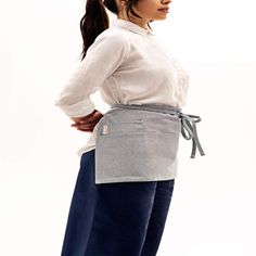 a woman standing with her hands on her hips wearing an apron and looking off to the side