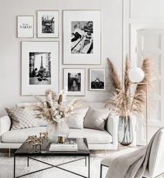 a living room filled with white furniture and pictures on the wall above it's coffee table