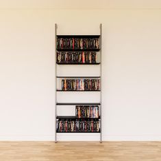 a tall metal shelf filled with dvd's on top of a hard wood floor