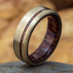 a wedding ring with wood inlays on top of a rock