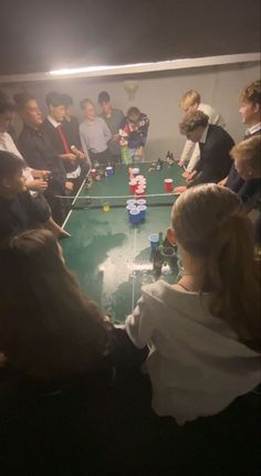 a group of people sitting around a table with cups on it and playing a game