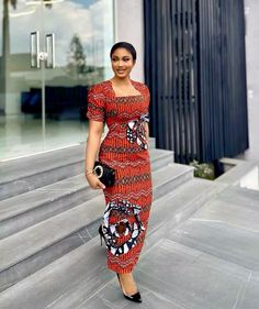 a woman in a red and black dress is standing on some steps with her purse