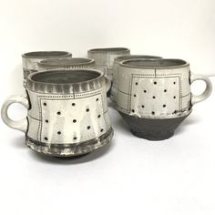 four silver cups sitting next to each other on a white surface