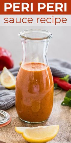 a glass bottle filled with sauce sitting on top of a wooden table next to sliced lemons