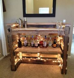 a bar made out of pallets with bottles and lights on the bottom, sitting in front of a mirror