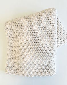 a white crocheted pillow on a white wall