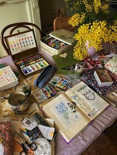 an assortment of art supplies on a table with yellow flowers in the backgrouf