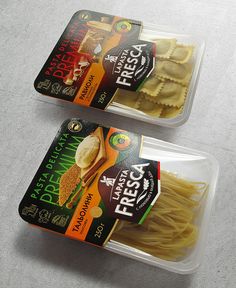 three packages of pasta sitting on top of a white table next to each other in plastic containers