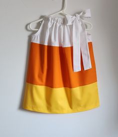 an orange, yellow and white dress hanging on a hanger