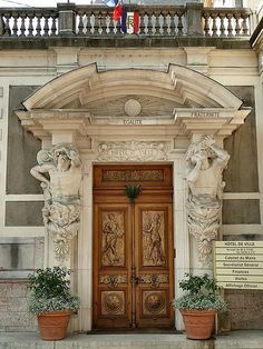 an old building with two wooden doors and some planters on the front steps,