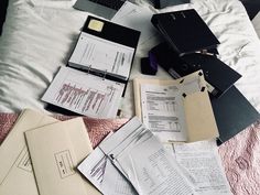 many papers are spread out on the bed with laptops and notebooks around them