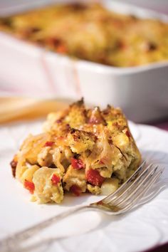 a white plate topped with a casserole covered in cheese and vegetables next to a fork