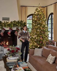 a man standing in front of a christmas tree next to a living room filled with furniture