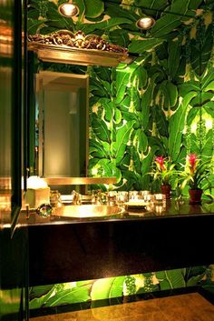 the bathroom is decorated in green and gold with palm leaves on the wall behind it