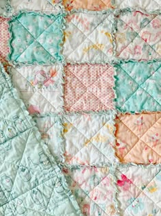 a close up of a patchwork quilt with pastel colors and flowers on it