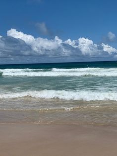 a man riding a surfboard on top of a wave in the ocean next to a sandy beach