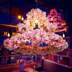 a chandelier with pink flowers hanging from it's ceiling in a restaurant