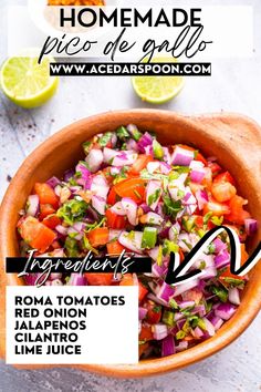 a wooden bowl filled with chopped vegetables on top of a white table next to limes