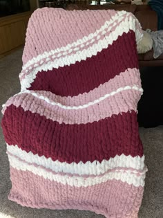 a pink and red blanket sitting on top of a couch