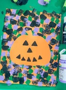 a paper plate with a pumpkin on it next to paint and other crafting supplies