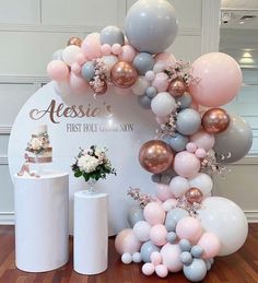 the balloon arch is decorated with pastel pink, grey and white balloons for a first birthday celebration