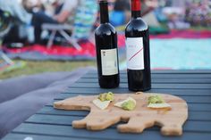 two bottles of wine sitting on top of a wooden cutting board next to each other