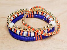 This Listing is for 4  single bracelets or a stack of 4 The GameDay Royal Blue & Orange Bracelets are sold as 4 single bracelets or in a stack of 4. The bracelets are beautiful royal blue & orange and mixed with gold-plated beads.  **Bracelets Features: 1.  4mm Gold plated bead bracelet with orange seed beads bracelet. 2. 6mm Royal blue, orange heishi bead bracelet with gold disc. 3. 8mm White Jade, and 5mm gold plated bead bracelet. 4. 6mm White, blue, and orange heishi bracelet with gold disc. Each bracelet is handmade to order. Need a custom size, reach out to us. **How to find your bracelet size - Measure around your wrist with a flexible tape measure - Please make sure to order 1/2 inch larger for fitted bracelets or 1" larger for looser bracelets. *MATERIALS AND DETAILS - High-qualit Blue Stacked Bracelets As Gift, Blue Stacked Bracelets For Gift, Blue Stacked Round Bead Jewelry, Blue Stacked Bracelets Gift, Blue Stacked Bracelets With Round Beads, Orange Beaded Heishi Bracelets, Blue Stacked Beaded Bracelets, Handmade Orange Heishi Beads Jewelry, Hand-strung Orange Beaded Bracelets For Festival