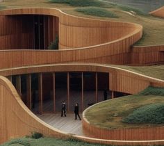 two people are standing in the middle of a building made out of wooden slats