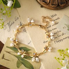 Blossom into style with our Golden Lily of The Valley Bracelet, where floral charm meets golden elegance. This bracelet is a petal-perfect addition to your ensemble, adding a touch of nature's brilliance to your wrist. Let it be a blooming statement piece that reminds you to "grow with grace" and "bloom where you are planted." Flaunt your flower power with this delightful accessory! DETAILS Plating: 18k Gold Materials:   18K Gold on Brass, Cubic Zirconia, Enamel, Pearl Measurements: Length: 6. Adjustable Gold Pearl Flower Bracelet, Gold Flower Bracelets For Wedding, Elegant Flower Decoration Bracelets For Gift, Adjustable Gold Jewelry With Flower Decoration, Elegant Crystal Bracelet With Flower Charm, Delicate Gold-plated Bracelet For Wedding, Delicate Gold Plated Bracelet For Wedding, Delicate Gold Bracelet With Flower Charm, Delicate Gold Bracelets With Flower Charm