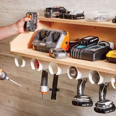 a man is holding two drillers in front of a shelf filled with various tools