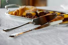 two serving trays filled with pastries on top of a white tablecloth covered table