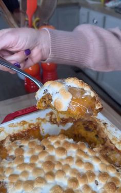 a person holding a spoon over a plate with food on it and another hand reaching for something