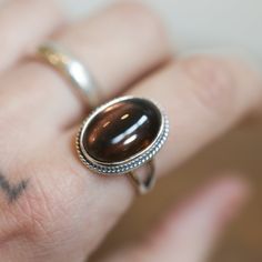 Beautiful, rich earthy, Smoky Quartz is featured in this classic, western statement ring. The LBJ Boho Ring design looks and feels like it was made by a master silversmith from another time. Perfect to enhance this love;ly Smoky Quartz, the boho, classic design with the .925 Sterling Silver twist wire and double, half-round split shank make it feel like you're sliding on something that someone will still wear in 50 years. This lovely, translucent, and sparkling warm, taupe grey-colored ring is created using traditional silversmithing techniques in my Baltimore, MD studio. Smoky Quartz measures 13x18mm Ring Top Measures 15x20mm All .925 Sterling Silver Smokey Quartz is an excellent grounding stone. It disperses fear, lifts depression and negativity and brings emotional calmness. While relie Smoky Quartz Brown Rings For Gifts, Smokey Quartz Ring, Smokey Quartz Rings, Silversmith Rings, Chloe Ring, Handmade Brown Smoky Quartz Jewelry, Smokey Quartz Jewelry, Smoky Quartz Ring, Purple Rings