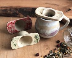 three tea cups and two spoons sitting on a table next to some dried herbs