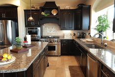 a large kitchen with granite counter tops and stainless steel appliances, along with dark wood cabinets