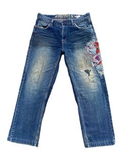 a pair of blue jeans with patches on the side and an embroidered design on the back