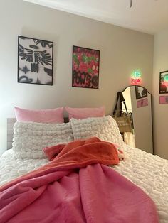 a bed with pink blankets and pictures on the wall next to it in a bedroom